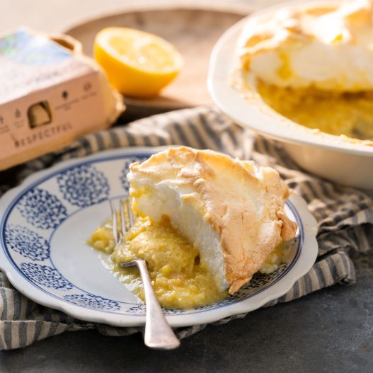 A slice of the very lemony bread crumb pudding sits on a white and blue plate.